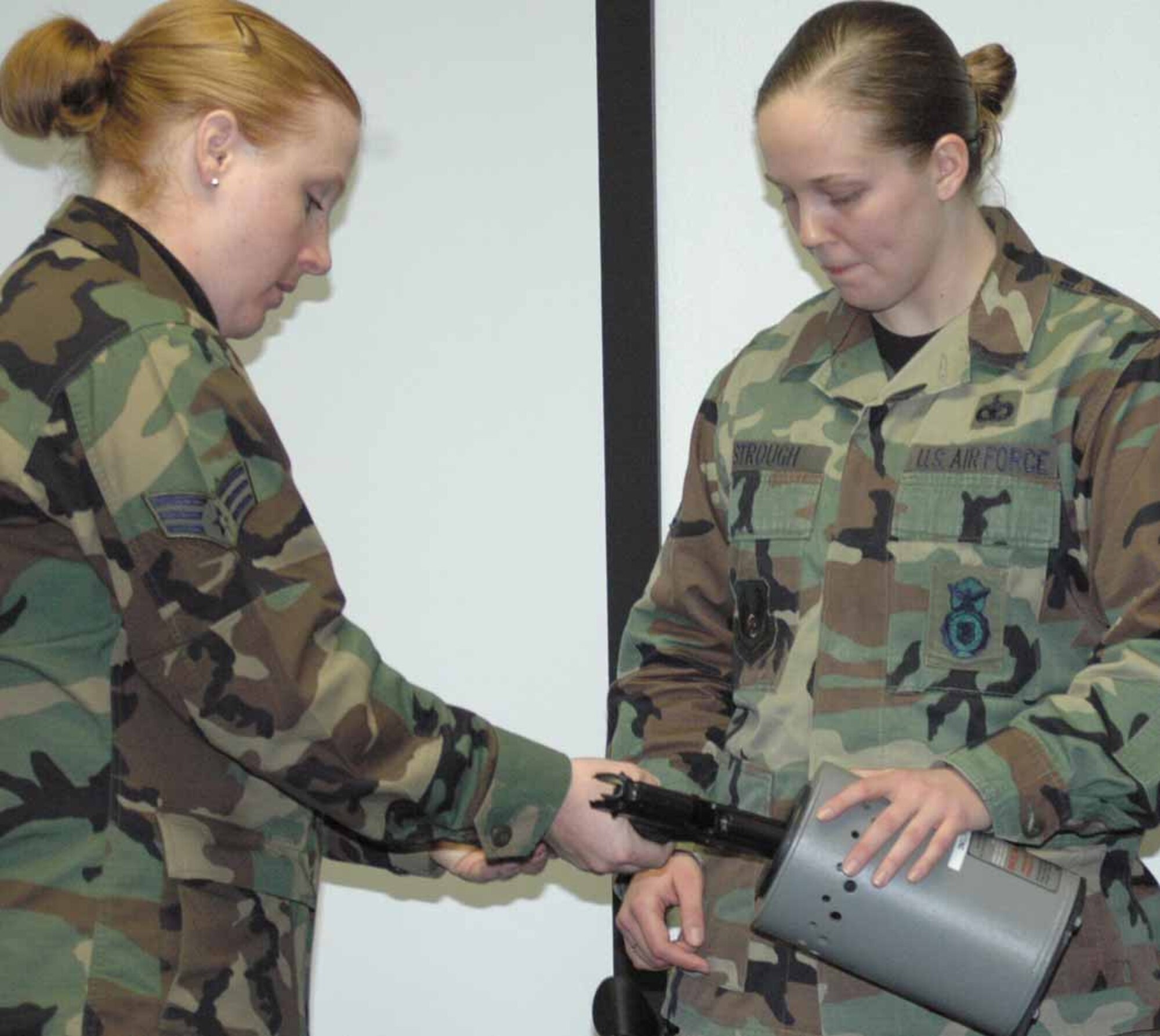 Staff Sgt. Jennifer Strough helps Senior Airman Lisa Vincelette in making her weapon safe for turning in.   (Air Force photo by Danielle Gregory)