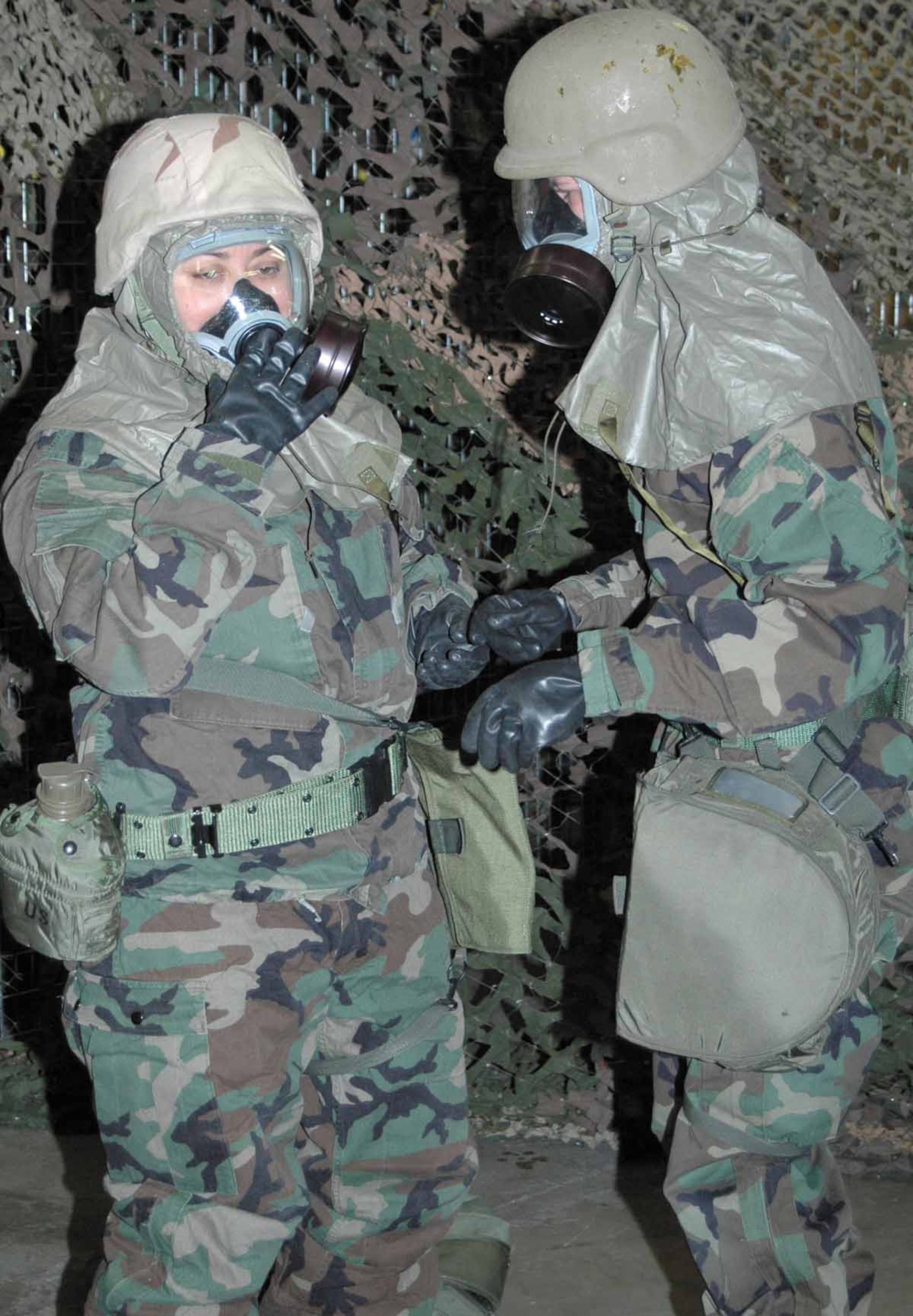 Two airmen help one another out with their chemical gear, during the survival refresher course held last Friday.  (Air Force photo by Danielle Gregory)