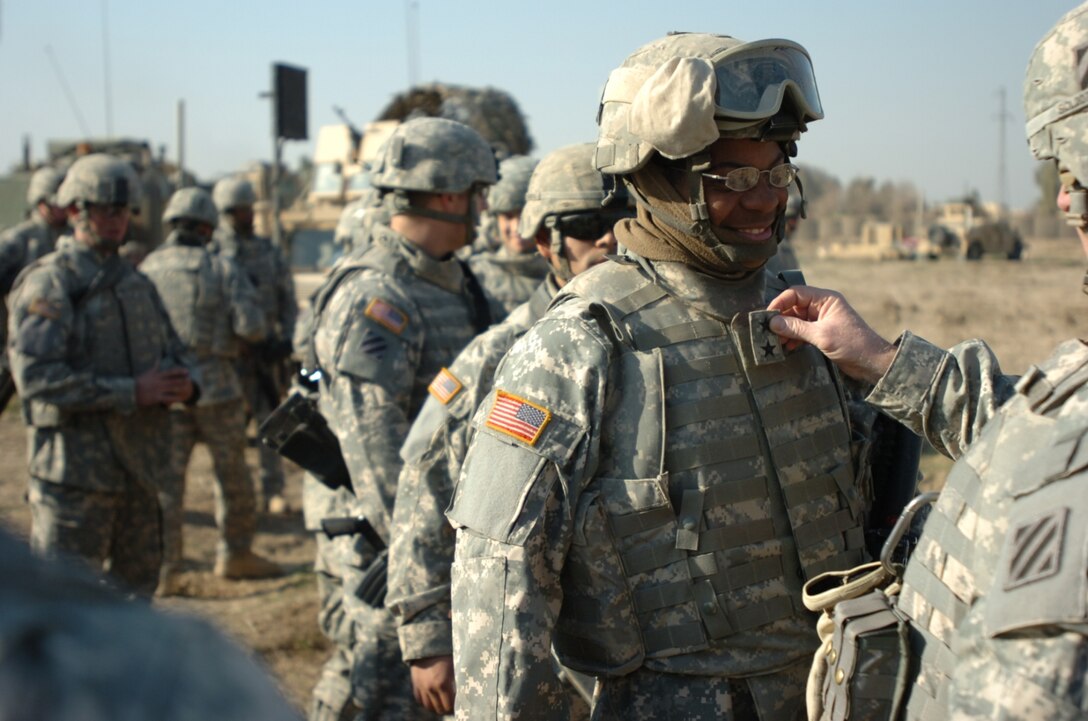 Army Pvt. Jamie Bennett, from Columbia, S.C., a heavy construction equipment operator with 3rd Platoon, 535th Equipment Support Company, 479th Engineer Battalion, gets a momentary promotion to two-star general by Army Maj. Gen. Rick Lynch, commander of Multinational Division Center, during Lynch’s visit to Combat Outpost Meade, in Iraq, Jan. 16, 2008. Photo by Sgt. Michael Connors, USA 