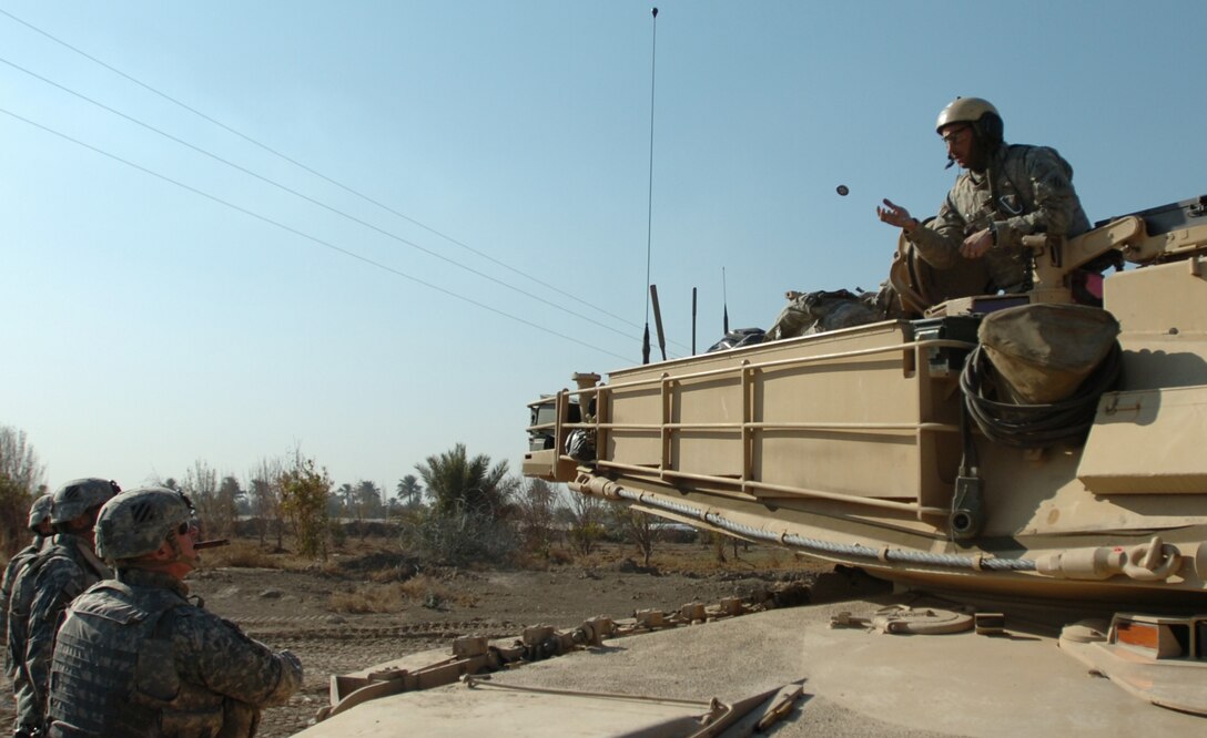 Army Staff Sgt. David Ortiz, from Chicago, a tank commander with Company D, 4th Battalion, 64th Armor Regiment, attached to Troop C, 6th Squadron, 8th Cavalry Regiment, attached to 2nd Brigade Combat Team, 3rd Infantry Division, sticks out his hand atop an Abrams tank to catch a personal coin from Army Maj. Gen. Rick Lynch, commander of Multinational Division Center, Jan 16, 2008. Photo by Sgt. Michael Connors, USA