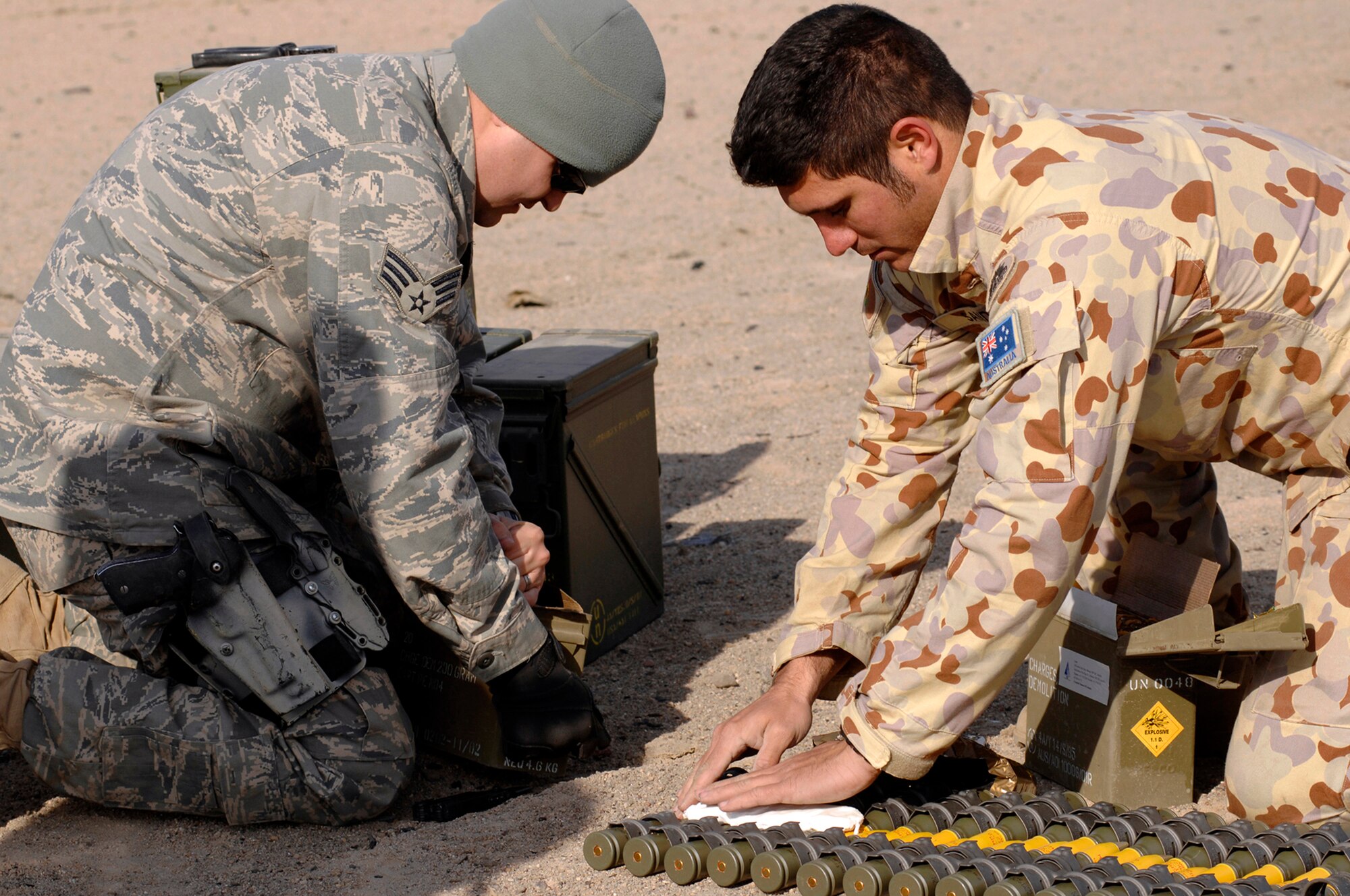 Senior Airman Charles Howell (left) and Australian Army Cpl. Nathan Sandow lay down P-4 explosive material over ammunition for a controlled detonation Jan. 18 in the Southwest Asia. Controlled detonations are done at an explosive ordnance disposal range to destroy unserviceable munitions. Airman Howell is with the 386th Expeditionary Civil Engineer Squadron Explosive Ordnance Disposal Flight and Corporal Sandow is with the Australian Army Force Level Logistic Asset unit. (U.S. Air Force photo/Senior Airman Patrick Dixon) 