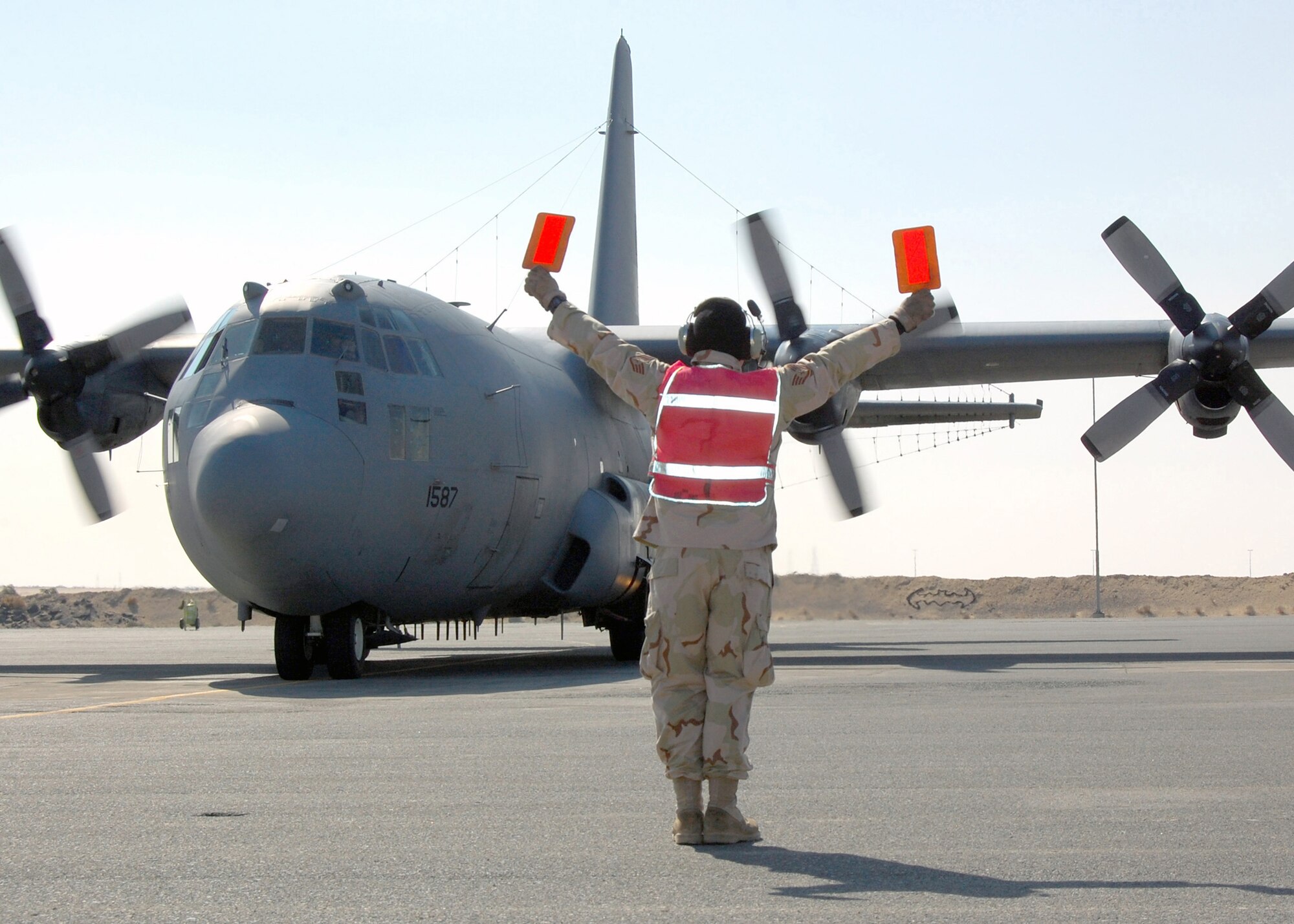 Staff Sgt. Jeffrey Weeks, 386th Expeditionary Aircraft Maintenance Squadron, marshals an E-C130H Compass Call on the flightline. The E-C130H Compass Call system employs offensive counter-information and electronic attack capabilities which integrate and synchronize U.S. and coalition tactical air, surface, and special operations forces. (U.S. Air Force photo/Capt Jason L. McCree)  
