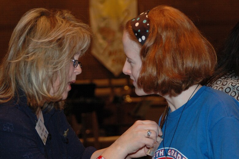 Elise Spoor, STARBASE staff, pins "wings" on an Apollo Elementary graudate of the STARBASE program. Approximately 170 Apollo students participated in STARBASE's 300th graduation ceremony Friday, Jan. 25, held at Asbury United Methodist Church, Bossier City, La. (U.S. Air Force photo/Master Sgt. Sherri Bohannon)