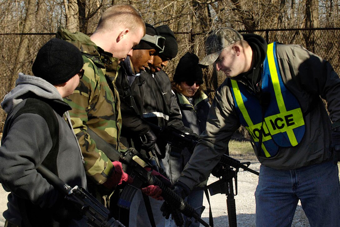 SCOTT AIR FORCE BASE, Ill. -- Tech. Sgt. Richard Reed, 375th Security Forces Squadron security forces trainer, shows fellow 375th Airlift Wing servicemembers who are playing the role of terrorists how to properly charge their weapons before a simulated attack on 375th Logistics Readiness Squadron members. (U.S. Air Force photo by Airman 1st Class Jonathan Lovelady)