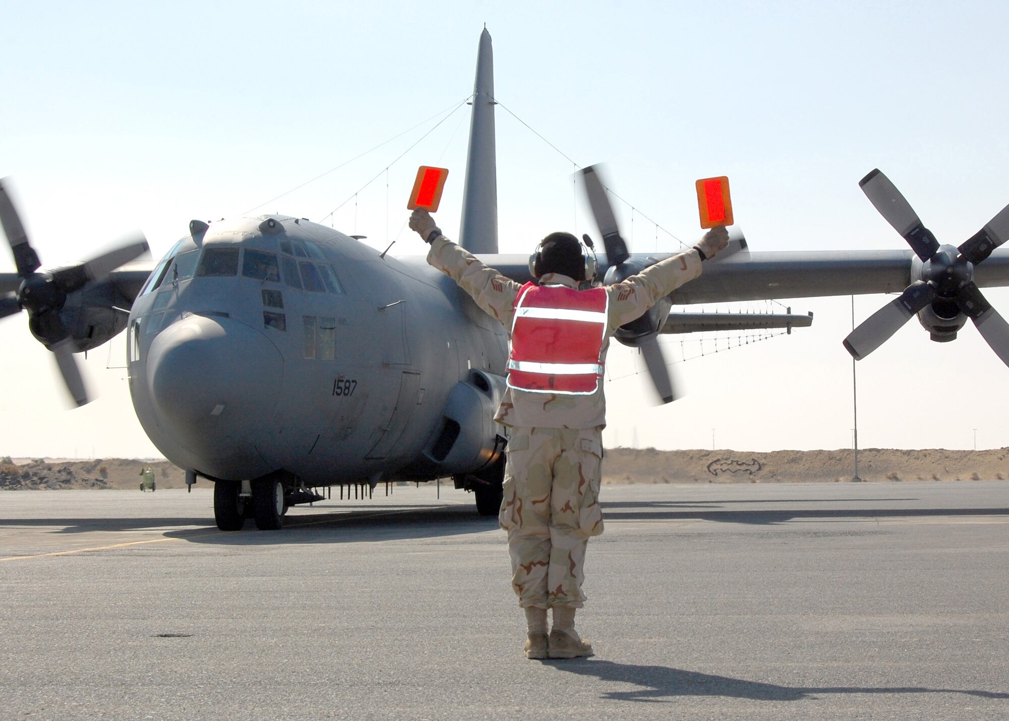 PERSIAN GULF - Staff Sgt. Jeffrey Weeks, 386th Expeditionary Aircraft Maintenance Squadron, marshals an EC-130H Compass Call on the flightline.  The EC-130H Compass Call system employs offensive counter-information and electronic attack capabilities which integrate and synchronize U.S. and Coalition tactical air, surface, and special operations forces. (U.S. Air Force photo/Capt Jason L. McCree)