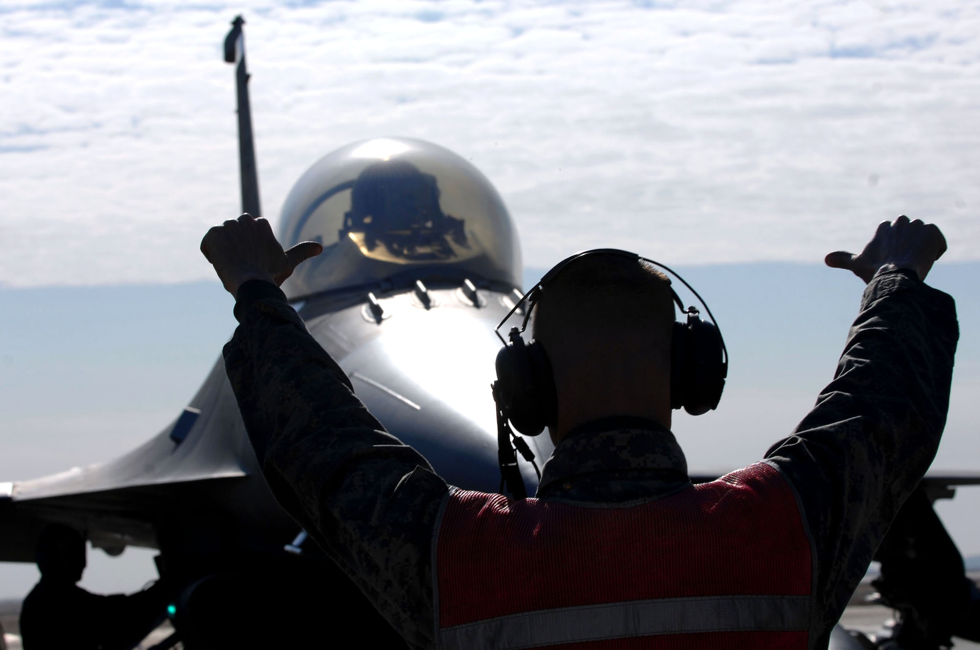Staff Sgt. Jeremy Lewis gives the "chalks in" signal to Capt. Travis Keenan before de-arming his F-16 Fighting Falcon Jan. 19 at Balad Air Base, Iraq. Communication between crew chiefs and fighter pilots is done via head sets and hand signals. Sergeant Lewis is a 332nd Expeditionary Aircraft Maintenance Unit crew chief and Captain Keenan is a 22nd Expeditionary Fighter Squadron pilot . Both Sergeant Lewis and Captain Keenan are from Spangdahlem Air Base, Germany.(U.S. Air Force photo/Senior Airman Julianne Showalter) 