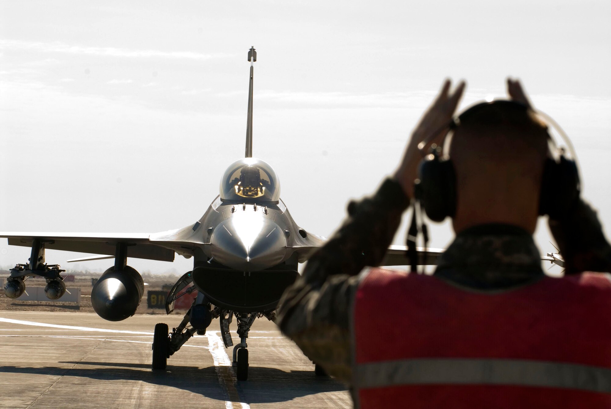 Staff Sgt. Jeremy Lewis marshals an F-16 Fighting Falcon in the arm/de-arm pit  Jan. 19 at Balad Air Base, Iraq. Before and after all F-16 missions, the aircrafts munitions are armed and de-armed inside the pit to maintain safety and security. Sergeant Lewis is a 332nd Expeditionary Aircraft Maintenance Unit crew chief deployed from Spangdahlem Air Base, Germany. (U.S. Air Force photo/Staff Sgt. Joshua Garcia) 
