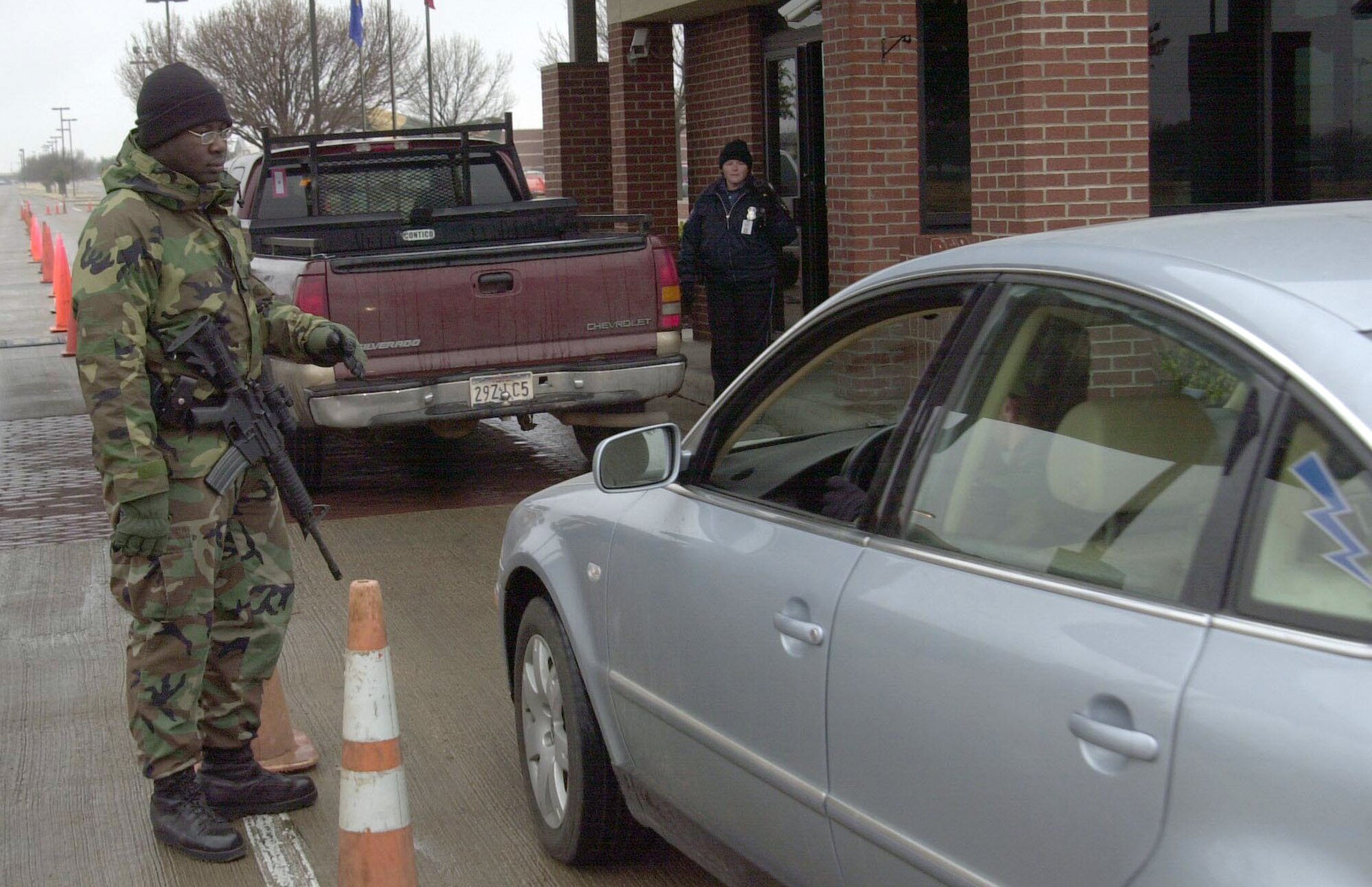 Airman 1st Class Warren Moultrie, 17th Security Forces Squadron installation entry controller, and Michele Chernick, installation security guard, check identification cards at Goodfellow Air Force Base's north gate late Wednesday morning. Airman Moultrie and Ms. Chernick periodically checked identification at two different positions on the temporary south-bound entry lane to the base in order to facilitate the flow of motorists entering the base after Col. Richard Ayres, 17th Training Wing commander, authorized delayed reporting to work as a safety precaution due to hazardous road conditions caused by a cold front that swept through the local area. More than a dozen vehicle accidents were reported to local-area law enforcement agencies Wednesday morning, and the Texas Department of Transportation closed off several main roadways in and around San Angelo as a precautionary measure. (U.S. Air Force photo by Senior Airman Luis Loza Gutierrez)