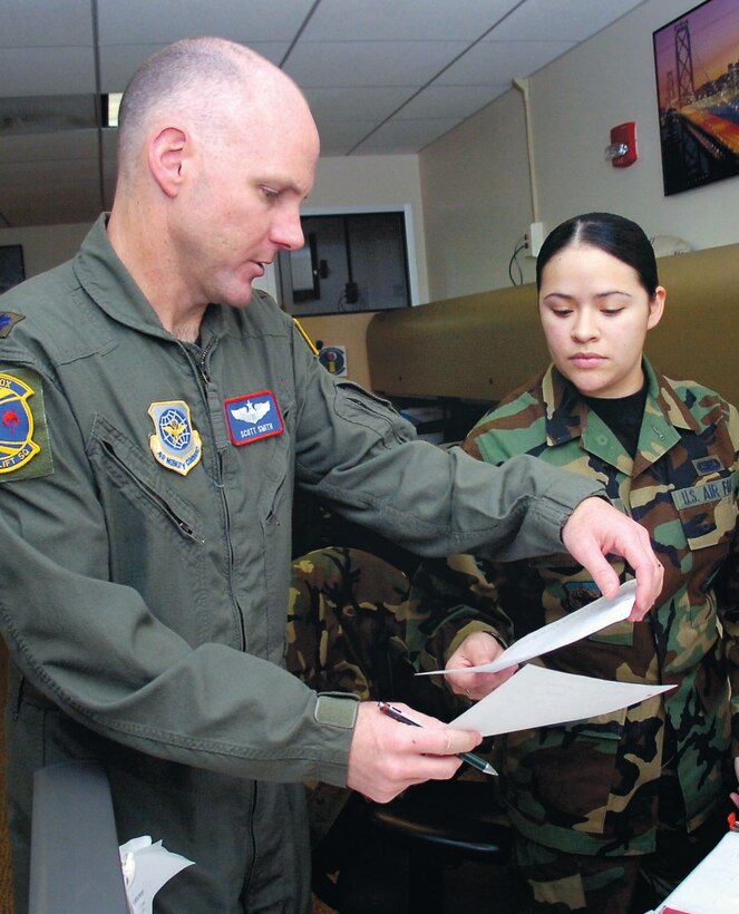 Lt. Col. Scott Smith, 1st Airlift Squadron missions operations duty officer, confirms message traffic flight plans with Staff Sgt. Rosalinda Gonzalez, 89th Operations Support Squadron mission specialist.(US Air Force/Bobby Jones)