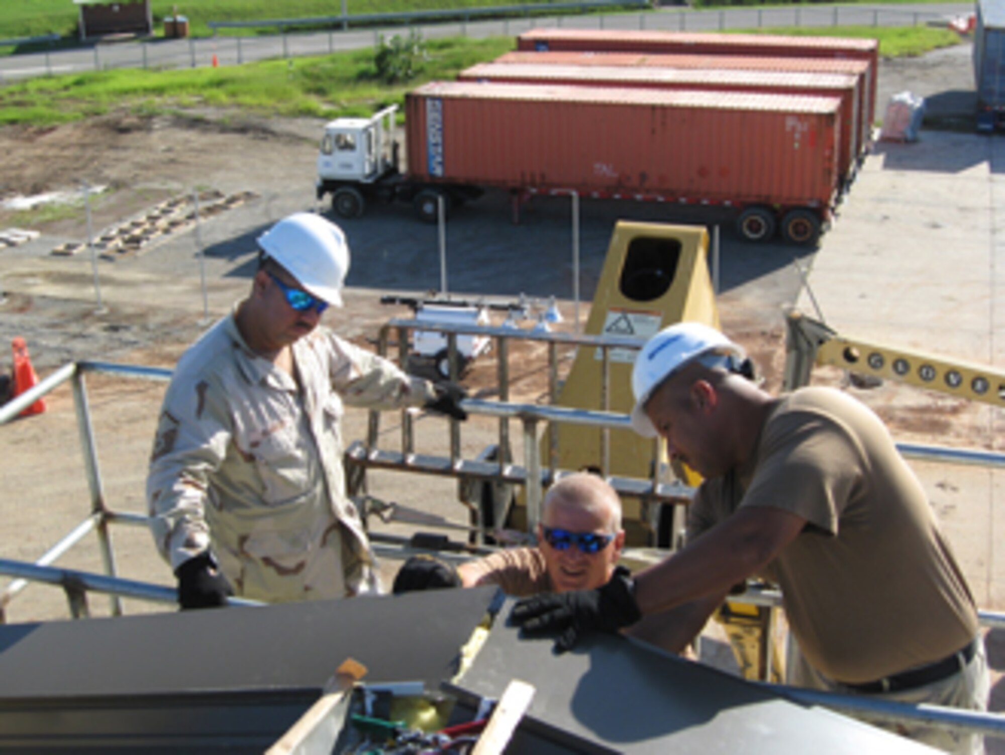 Master Sgt. Moses Alvarado, Technical Sgt. Paul Gomez and Master Sgt. Karl Childress are standing on a scafold, working on the Expeditionary Legal Complex. (U.S. Air Force photo)