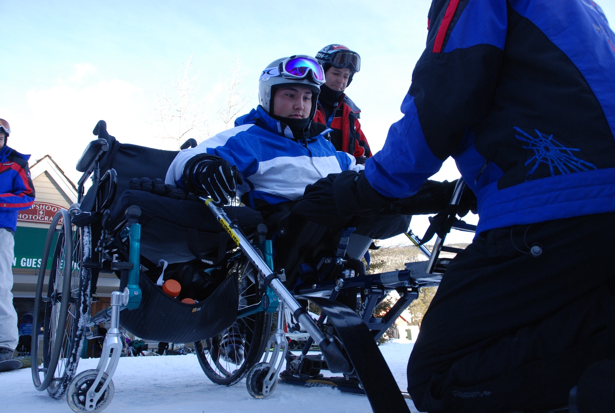 Airman 1st Class Kevin Krogh (center), with help from an Adaptive Adventures, Inc. instructor, mounts a modified ski basket built for disabled persons Jan. 26. Airman Krogh, who was injured during an automobile accident, is an F-22 Raptor weapons loaders assigned to Langley AFB, Va. Airman Krogh, together with several other disabled servicemembers, took advantage of the company's free ski lessons offered during the annual SnoFest military community event in Keystone, Colo. (U.S. Air Force photo/Senior Airman Stephen Collier)