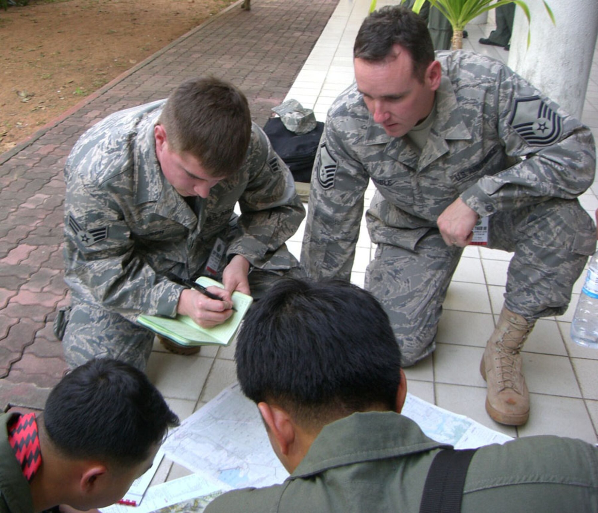 KORAT ROYAL THAI AIR BASE, Thailand -- Senior Airman Robert Olson (left) and Master Sgt. Joe Ruble (right), 3rd Air Support Operations Squadron of Fort Wainwright, Alaska, go over coordinates for a close air support mission with their counterparts of the Royal Thai Air Force Jan. 26. Airman Olson and Sergeant Ruble are Joint Terminal Attack Controllers and are participating in Exercise Cope Tiger '08, a Thai- and U.S.-sponsored multilateral joint and combined field training exercise, and humanitarian/civic assistance exercise. Cope Tiger enhances combined readiness and interoperability, reinforces U.S. commitment to the Southeast Asian region, and demonstrates our capability to project combined and joint forces strategically in a multilateral environment. (U.S. Air Force photo by Capt. Renee Lee)