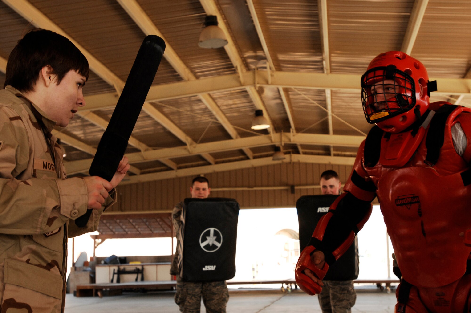 SOUTHWEST ASIA -- Airman 1st Class Amber Morton gets ready to defend herself from an attack from Airman 1st Class Tyler Brunner, in the red protective suit, Jan. 24, 2008, during self defense tactics training with batons at an air base in the Persian Gulf Region. The self defense training familiarizes Airmen with how to use non-lethal force to defend themselves. Airman Morton and Brunner are assigned to the 386th Expeditionary Security Forces Squadron and are deployed in support of Operation Iraqi Freedom. (U.S. Air Force photo/ Senior Airman Patrick Dixon)