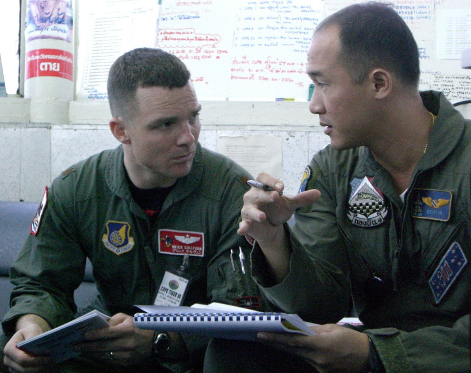 KORAT ROYAL THAI AIR BASE, Thailand -- Maj. Sean 'Brick' Sullivan, U.S. Air Force mission director of flying operations for Exercise Cope Tiger '08, discusses air traffic procedures with Maj. Tapanon 'Xenon' Dhanamon, F-16 pilot of the Royal Thai Air Force here Jan. 27. Cope Tiger is a  multilateral joint and combined field training and humanitarian and civic assistance exercise involving Thailand, Singapore and the United States. The Thai-, Singaporean-, and U.S.-hosted exercise enhances combined readiness and interoperability, reinforces U.S. commitment to the Southeast Asian region, and demonstrates U.S. capability to project combined and joint forces strategically in a multilateral environment. (U.S. Air Force photo by Capt. Renee Lee)
