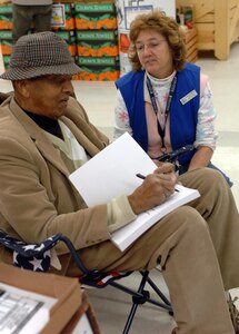 LANGLEY AIR FORCE BASE, Va. -- Retired U.S. Army Maj. Cecil Ward White autographs his latest book, “Give Me My Spirit Back--The Last of the Buffalo Soldier” for Mrs. Theresa Taylor, Langley commissary store associate Jan. 25. Major White spent a week at the Langley Commissary promoting his autobiography about his perseverance and pride of being a Buffalo Soldier during World War II. (U.S. Air Force photo/Airman 1st Class Chase Skylar DeMayo)