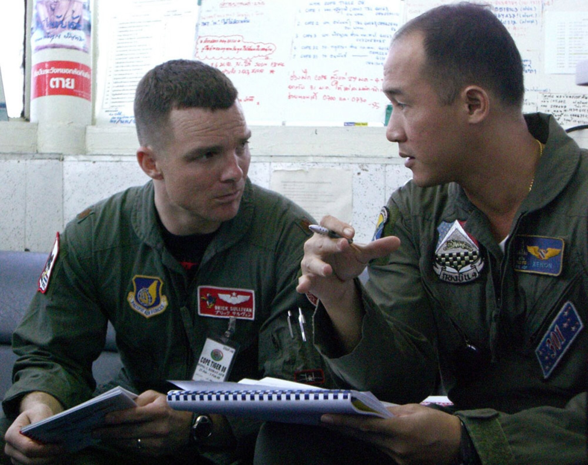 Maj. Sean Sullivan discusses air traffic procedures with Royal Thai air force Maj. Tapanon Dhanamon Jan. 27 at Korat Royal Air Base, Thailand. Cope Tiger 2008 is a multilateral joint and combined field training and humanitarian and civic assistance exercise involving Thailand, Singapore and the United States. The Thai-, Singaporean- and U.S.-hosted exercise enhances combined readiness and interoperability, reinforces U.S. commitment to the Southeast Asian region, and demonstrates the U.S. capability to project combined and joint forces strategically in a multilateral environment. Major Sullivan is the mission director of flying operations for Exercise Cope Tiger 2008, and Major Dhanamon is a Royal Thai air force F-16 pilot. (U.S. Air Force photo/Capt. Renee Lee) 
