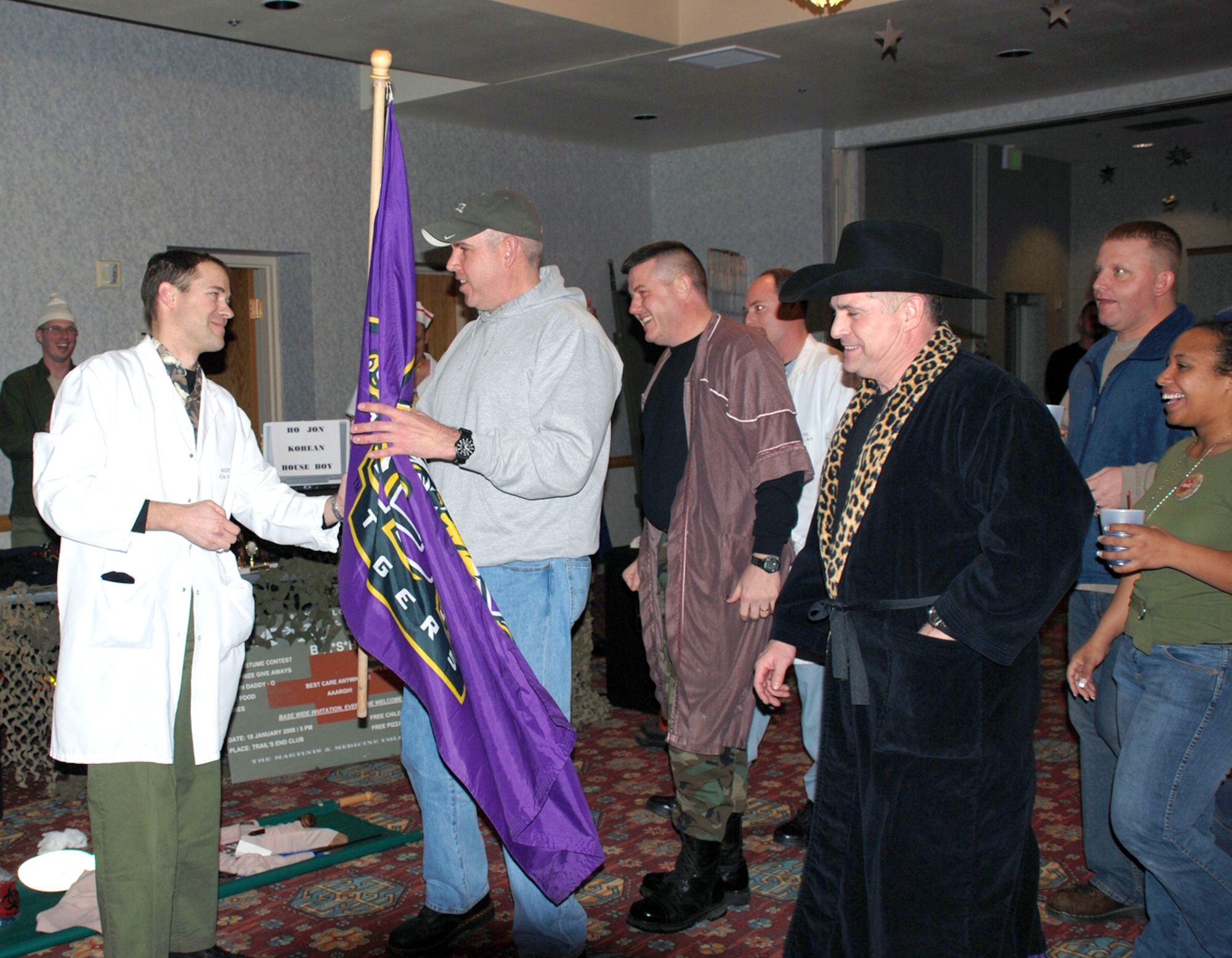 Maj. Dean Bartholomew, 90th MDOS, returns the hostage Louisiana State University school flag to members of the 90th Security Forces Group at the MASH Bash party Jan. 18 at the Trail’s End Club. The 90th MDG kidnapped precious keepsakes from the wing commander and group commanders and ransomed them off at the party. The LSU flag belonged to Colonel Martinez (U.S. Air Force photo/2nd Lt. Lisa Meiman).
