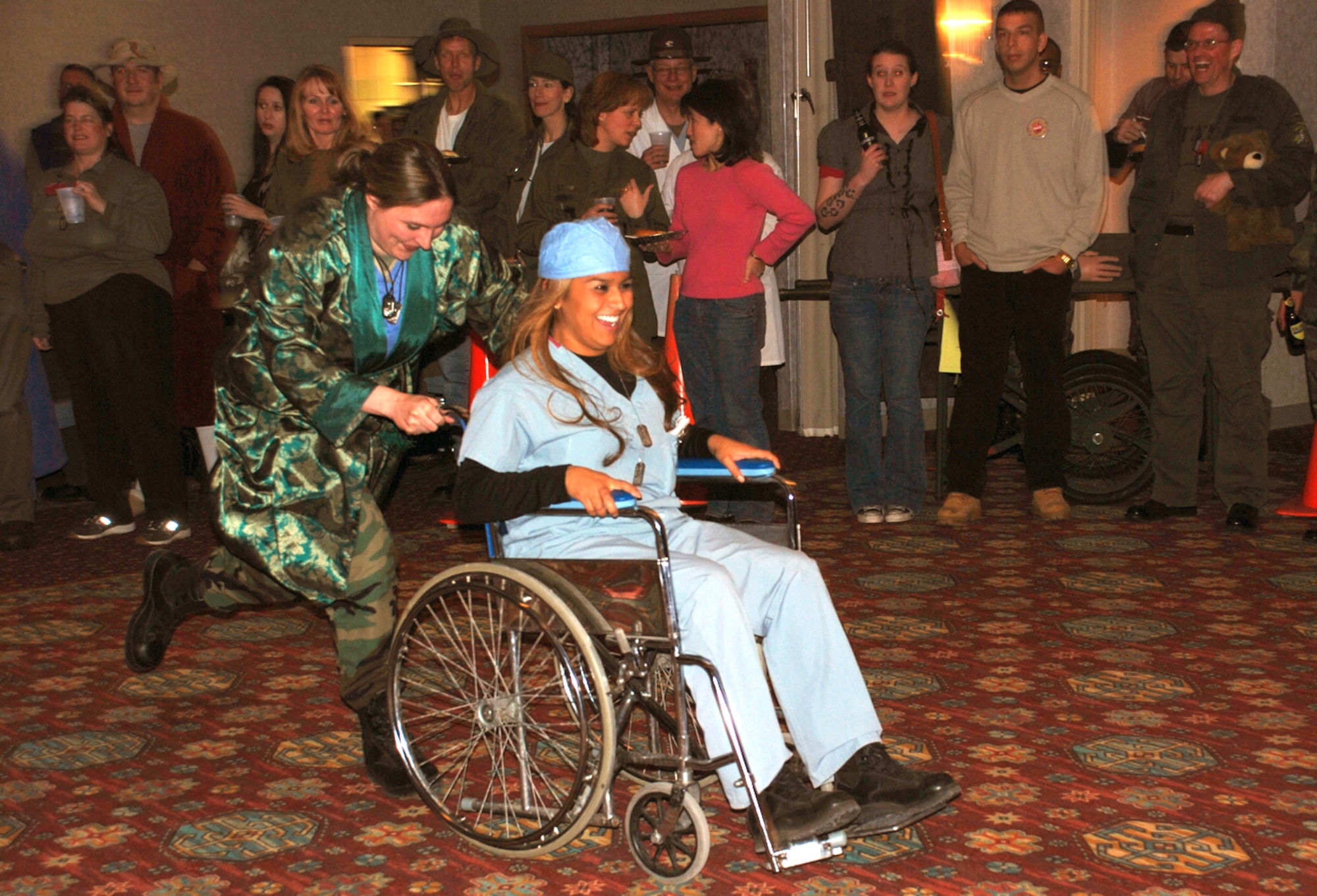 Lt. Col. Leigh Swanson, 90th Medical Operations Squadron commander, pushes Senior Airman Veronica Sena, 90th MDOS, through the Trail’s End Club during the wheelchair race competition at the MASH Bash party Jan. 18. The MASH Bash party, hosted by the 90th Medical Group, consisted of wheelchair races, a costume competition, food and dancing. The next large party at the Trail’s End Club is a Mardi Gras party hosted by the 90th Security Forces Group Feb. 1 (U.S. Air Force photo/2nd Lt. Lisa Meiman).