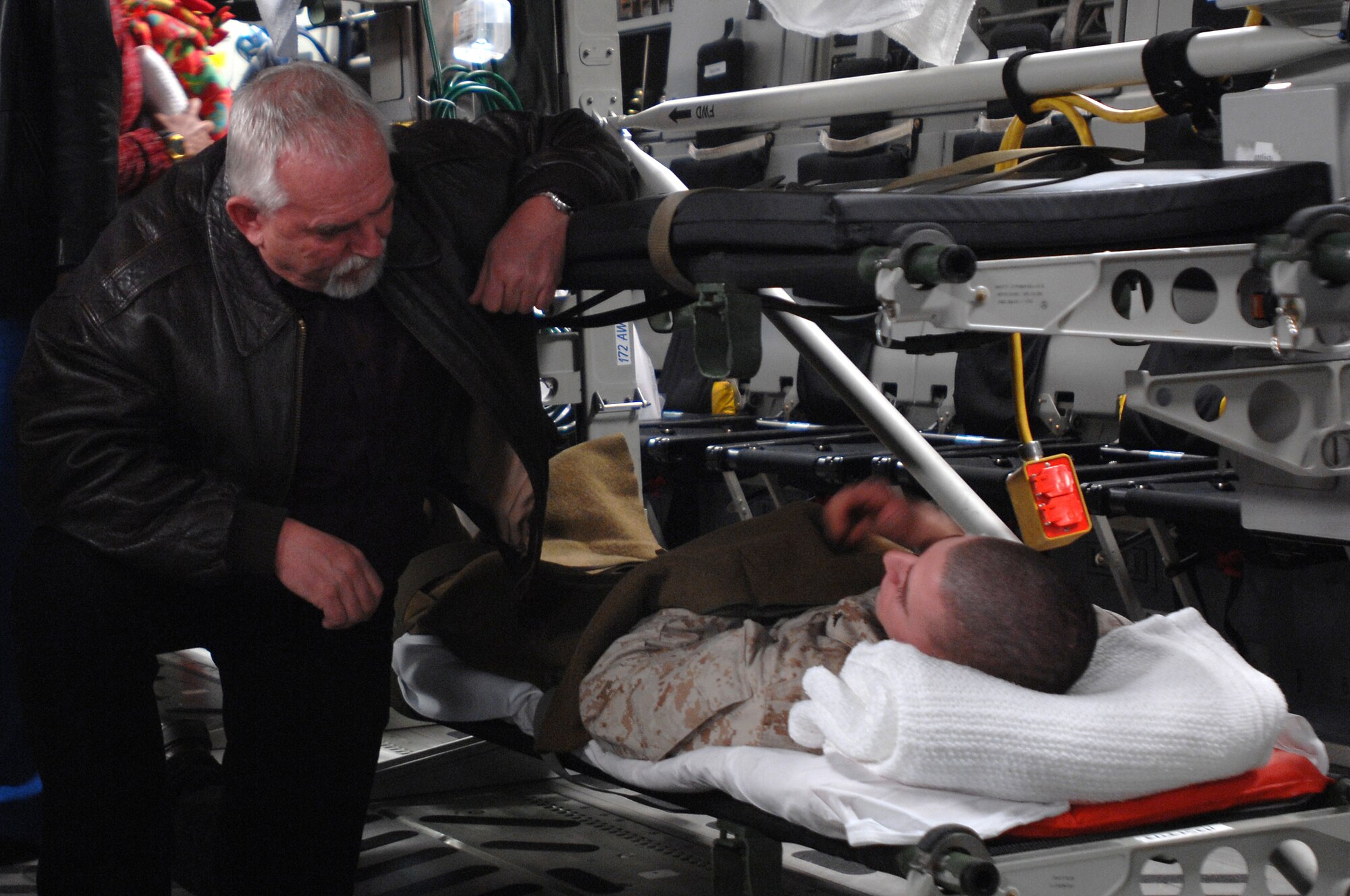 Actor John Ratzenberger visits with wounded military personal being loaded onto an aeromedical evacuation flight during his recent visit to Ramstein Air Base Jan. 25. Mr. Ratzenberger and friends, Medal of Honor recipients Mike Thornton and Drew Dix, and actor Gary Sinise visited Ramstein to help boost morale and say thanks for all the great work accomplished by the armed forces. (U.S. Air Force photo/Airman 1st Class Kenny Holston)
