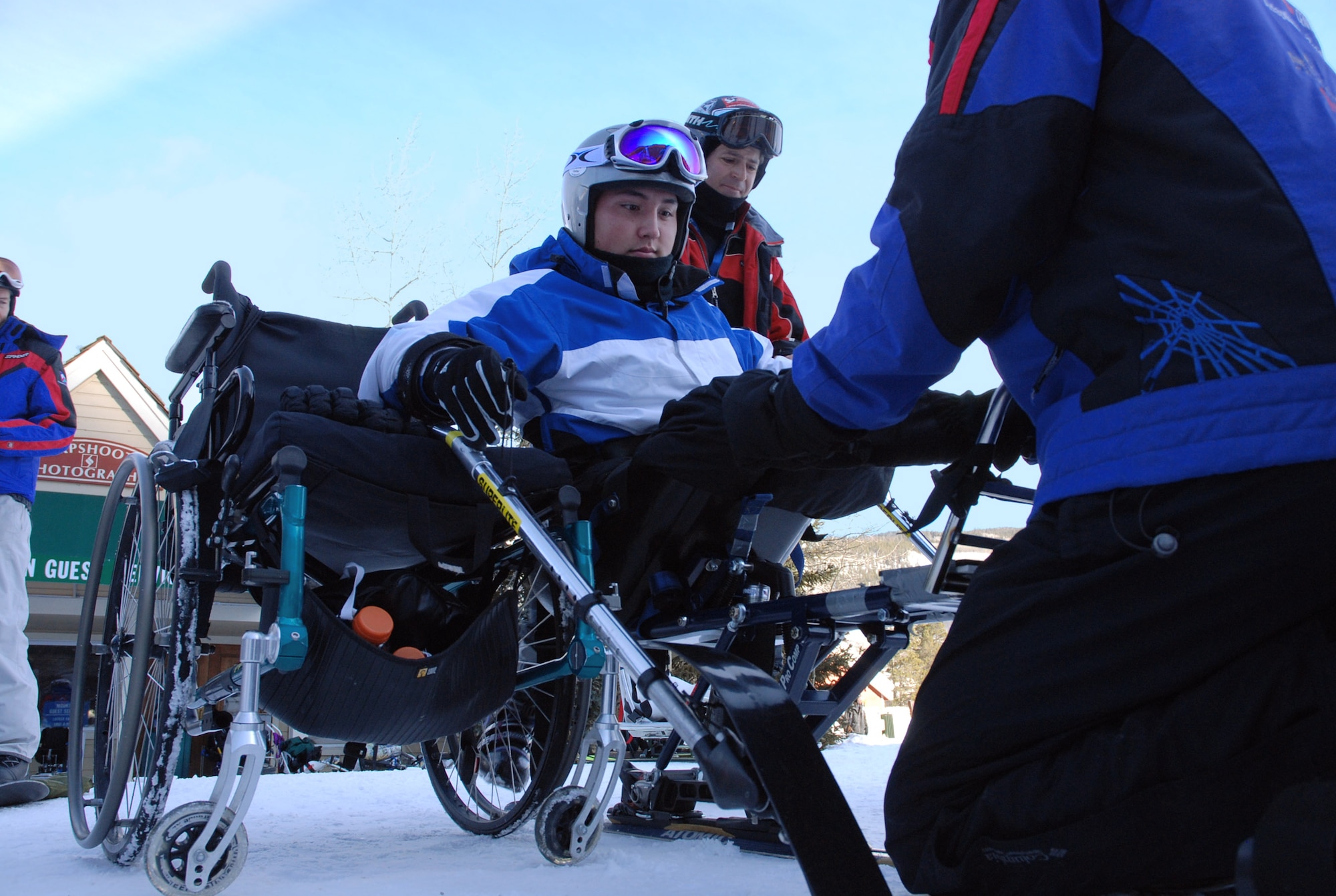 Airman 1st Class Kevin Krogh (center), with help from an Adaptive Adventures, Inc., instructor, mounts a modified ski basket built for disabled persons Jan. 26 at the annual SnoFest military community event in Keystone, Colo.  Airman Krogh, who was injured during an automobile accident, is an F-22 Raptor weapons loaders assigned to Langley Air Force Base, Va. Airman Krogh, together with several other disabled servicemembers, took advantage of the company's free ski lessons offered during the military community event.  (U.S. Air Force photo/Senior Airman Stephen Collier) 