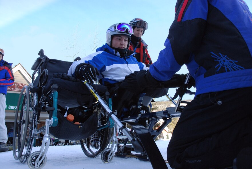 Airman 1st Class Kevin Krogh (center), with help from an Adaptive Adventures, Inc., instructor, mounts a modified ski basket built for disabled persons Jan. 26 at the annual SnoFest military community event in Keystone, Colo.  Airman Krogh, who was injured during an automobile accident, is an F-22 Raptor weapons loaders assigned to Langley Air Force Base, Va. Airman Krogh, together with several other disabled servicemembers, took advantage of the company's free ski lessons offered during the military community event.  (U.S. Air Force photo/Senior Airman Stephen Collier) 