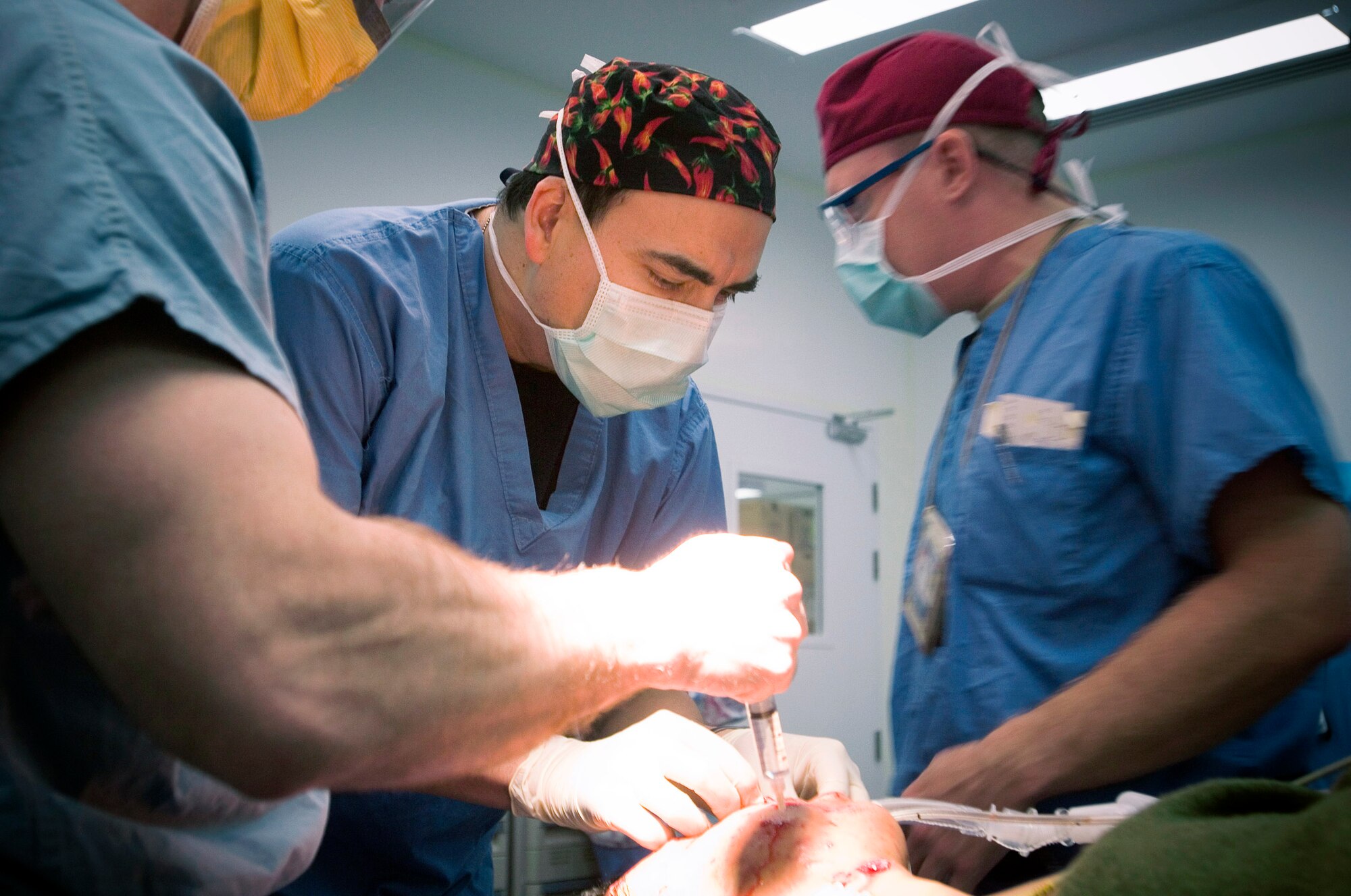 Capt. George Moctezuma, an operating room nurse, looks over the face of a wounded Iraqi security forces member at the Air Force Theater Hospital here. The patient's face was peppered with stone pebbles from a blast. According to Captain Moctezuma, the human face is more disease resistant than most bodily tissue. The captain is deployed from Wilford Hall Medical Center, San Antonio, Texas. (U.S. Air Force photo/Tech. Sgt. D. Clare) 
