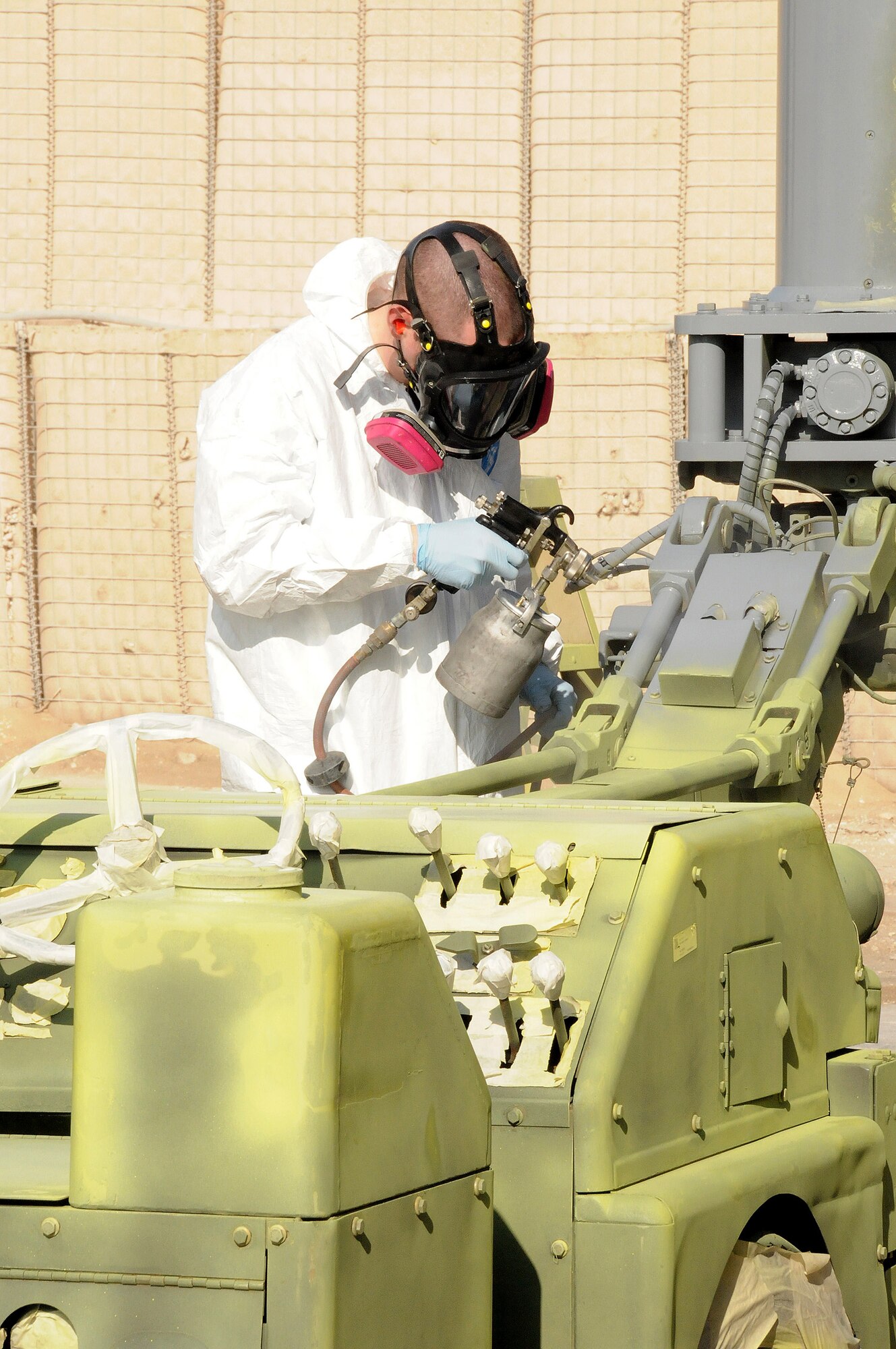 Senior Airman Geoffrey Sorensen from the 379th Expeditionary Maintenance Squadron, Fabrication Flight, Sheet Metal shop, paints a bomb lift Jan. 29. Every five to six years the bomb lifts have to be repainted in order to prevent corrosion.  Airman Sorensen is deployed from Hill Air Force Base, Utah.  (U.S. Air Force photo/Senior Airman Domonique Simmons)
