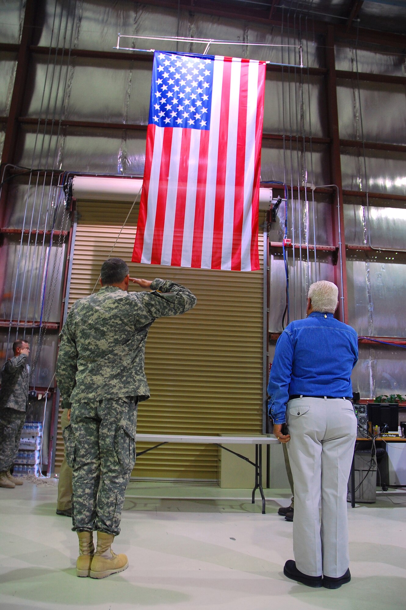 SOUTHWEST ASIA -- Army Lt. Col. Donald Rotramel (left), officer in charge of the Rapid Fielding Initiative outside of the continental United States, and Donald Costello (right), Equipment Fielder for Military Personnel Resources Incorporated, salute the U.S. flag during the playing of the U.S. national anthem Jan. 28, 2008, during a dedication and ribbon-cutting ceremony for the RFI's facility flag display building at a Life Support Area in the Persian Gulf Region. The flags are being hung to pay tribute to the more than the 2,000 soldiers who pass through the RFI's LSA facility each month before boarding flights for Iraq and Afghanistan. (U.S. Air Force photo/ Senior Airman Patrick Dixon)
 
