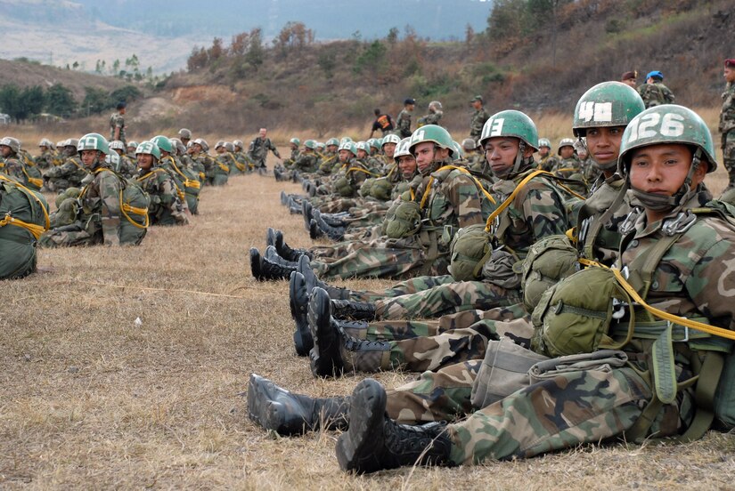 SOTO CANO AIR BASE, Honduras – Awaiting their turn to load onto an Army UH-60 Chinook for their first parachute jump, Honduran soldiers anxiously watch their peers descent from the helicopter which was used as the platform for their first jump.   More than 250 Honduran soldiers took their first step toward Airborne readiness when they leaped from the back of a U.S. Army helicopter Jan. 24 in a combined jump with U.S. Soldiers here. (U.S. Air Force photo by Tech. Sgt. William Farrow)