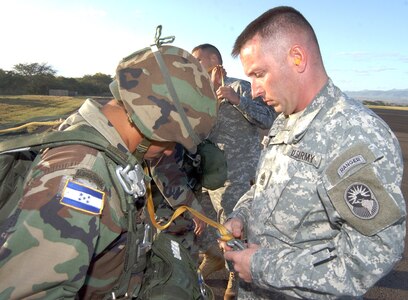 SOTO CANO AIR BASE, Honduras—Prior to the jump training, 1st Sgt. Lloyd Broom checks Honduran Army  Sergeant  German Elvir’s parachute security on the Joint Task Force-Bravo flight line Jan. 24. Sergeant Elvir was part of an initial five-person combined U.S.–Honduran evaluation team to jump from an Army UH-60 Chinook. The helicopter served as the platform for the Honduran Army’s efforts in training its soldiers in airborne tactics at the Honduran airborne troop headquarters at Tamara, Honduras. (U.S. Air Force photo by Martin Chahin)