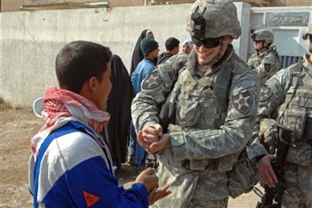 A soldier from the U.S. Army's 2nd Battalion, 12th Field Artillery Regiment, plays rock, paper, scissors with an Iraqi boy during a combined medical engagement at a clinic in Buhrez, Iraq, Jan. 25, 2008.  