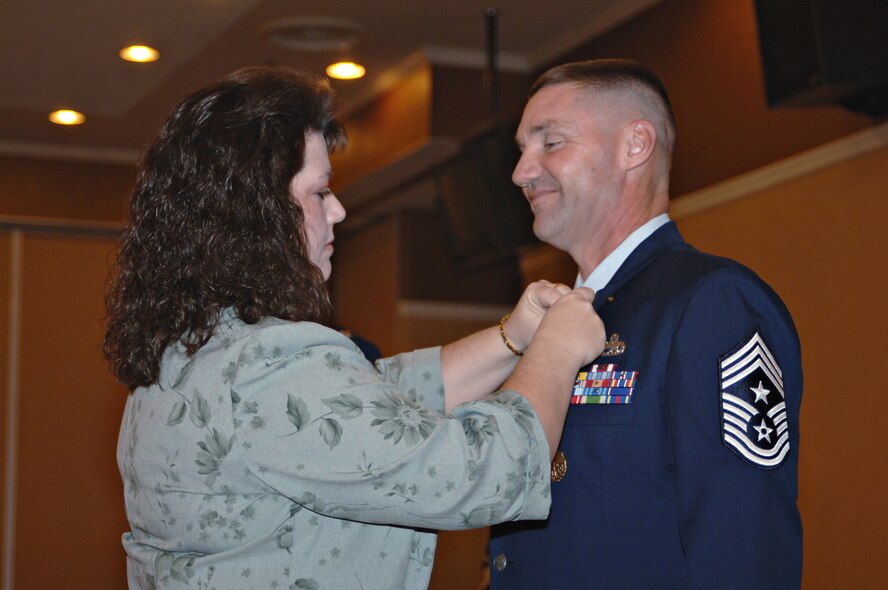 MISAWA AIR BASE, Japan -- Chief Master Sgt. Thomas Missel, 35th Fighter Wing command chief, receives his retirement pin from his wife, Beth, during a ceremony here Jan. 30, 2008. Chief Missel is retiring after 30 years of service to the Air Force. (U.S. Air Force photo by Airman 1st Class Benjamin Wilson)