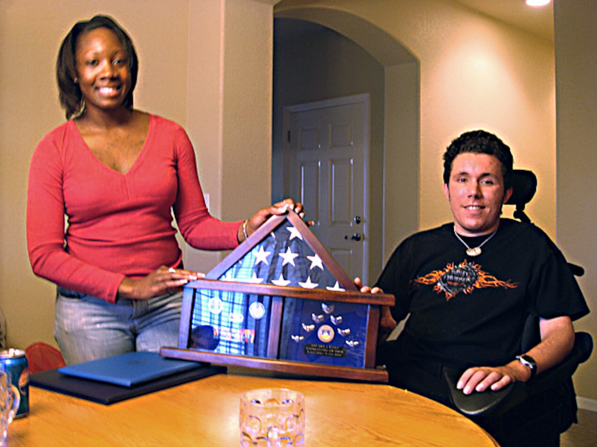 Tech. Sgt. Tahesha German (left), 95th Medical Group noncommissioned officer in charge of the referral management center, presents a retirement certificate and gift to Staff Sgt. Eric Raley on Dec. 27 at his home in Aurora, Colo. (Courtesy photo)