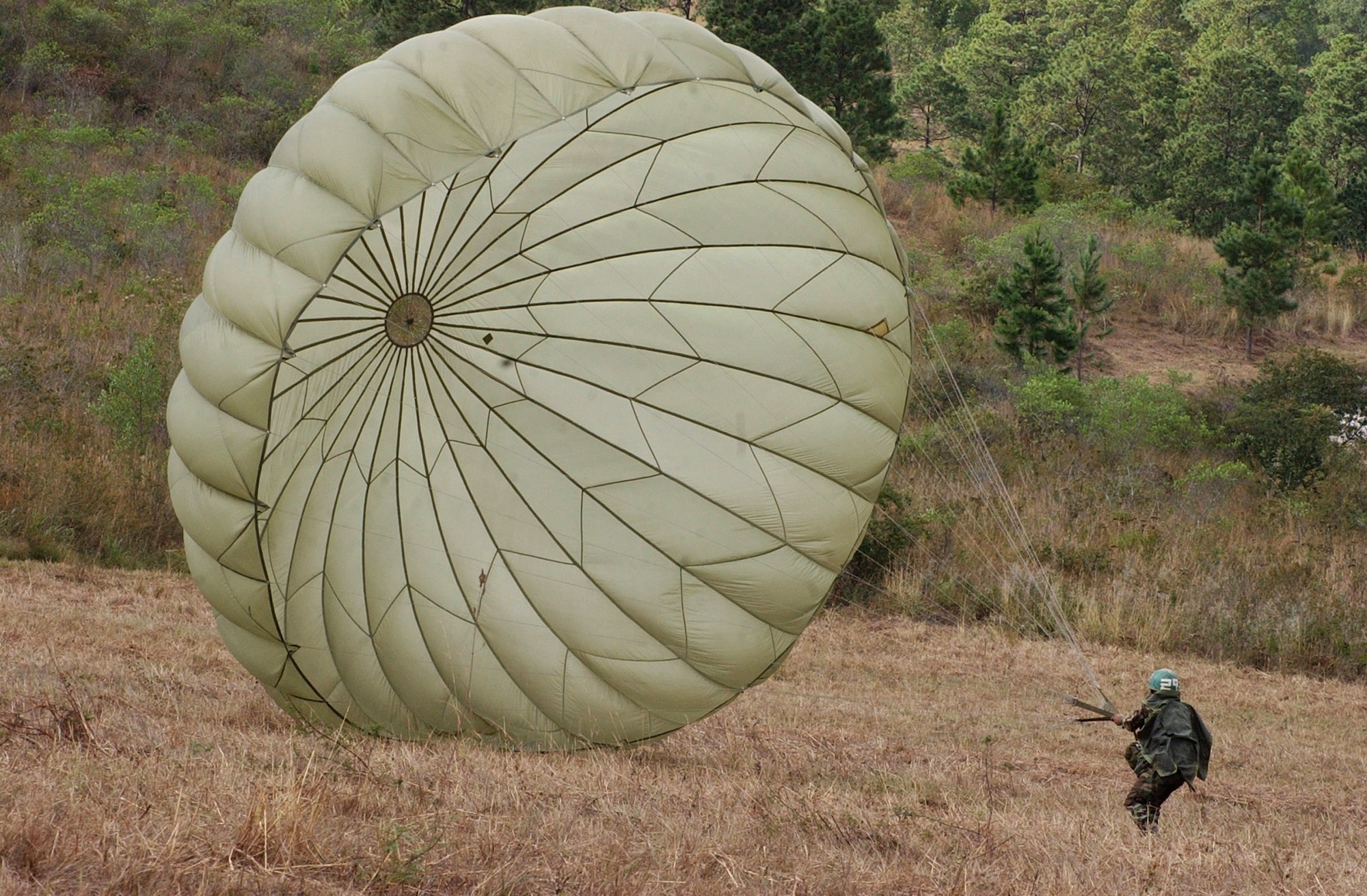 The wind pushes a Honduran soldier's chute after he lands safely Jan. 24 from his first leap from an Army CH-47D. The helicopter was used to in a combined training jump with U.S. Soldiers at the Honduran airborne troop headquarters at Tamara, Honduras. (U.S. Air Force photo by Martin Chahin) 
