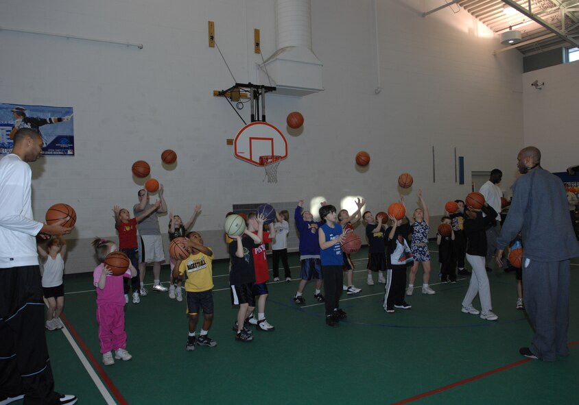 MINOT AIR FORCE BASE, N.D. -- Minot Skyrockets center Lee Scruggs and forward Kevin Rice help children develop their shooting form at the David C. Jones Youth Center here Jan. 26. The Skyrockets held a free basketball camp for youth, ages 5-18. (U.S. Air Force photo by Airman 1st Class Sharida Bishop)
