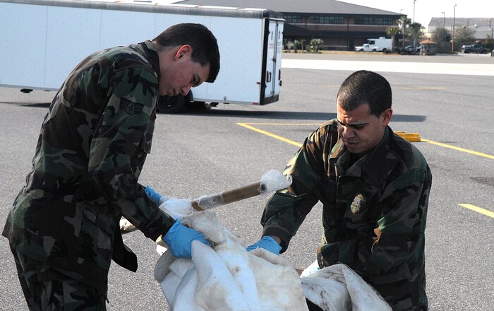 Senior Airman Justin Guy (left), 437th Maintenance Squadron, and Airman Basic John Bainter, 437 MXS, remove absorption pads from the Charleston AFB flightline Jan. 29 after a minor fuel spill. (U.S. Air Force photo/Tech. Sgt. Paul Kilgallon)