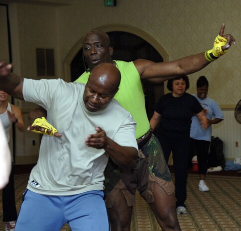 Fitness trainer Billy Blanks shows Capt. Jacqueline Young, 437th Communications Squadron, the proper workout technique during his workout session at the Charleston Club Jan. 28. (U.S. Air Force photo/ Airman 1st Class Katie Gieratz)