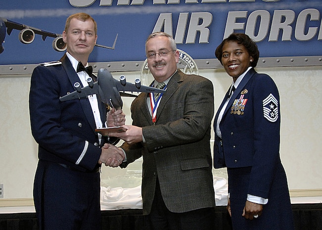 Col. John "Red" Millander, 437th Airlift Wing commander, and Chief Master Sgt. Bernice Belcer, 437th Airlift Wing command chief master sergeant, present the Civilian of the Year, Category three award to Jeffrey Garrett, 437th Civil Engineer Squadron, at the 437 AW Annual Awards dinner at the Charleston Club Jan. 24. (U.S. Air Force photo/Airman 1st Class Katie Gieratz)