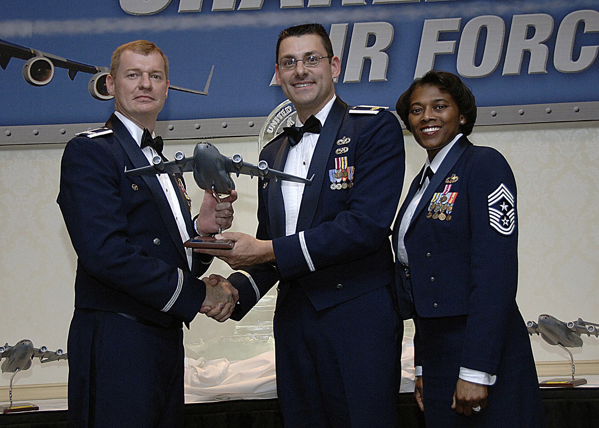Col. John "Red" Millander, 437th Airlift Wing commander, and Chief Master Sgt. Bernice Belcer, 437th Airlift Wing command chief master sergeant, present the Honor Guard Member of the year to Maj. James Petrick, 437th Logistics Readiness Squadron commander, who accepted the award on behalf of Airman 1st Class Brandon Harris, 437 LRS, who is currently deployed, at the 437 AW Annual Awards dinner at the Charleston Club Jan. 24. (U.S. Air Force photo/Airman 1st Class Katie Gieratz)