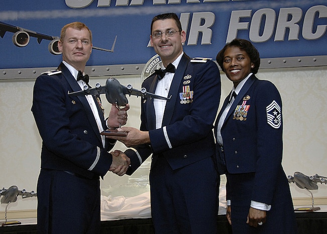 Col. John "Red" Millander, 437th Airlift Wing commander, and Chief Master Sgt. Bernice Belcer, 437th Airlift Wing command chief master sergeant, present the Honor Guard Member of the year to Maj. James Petrick, 437th Logistics Readiness Squadron commander, who accepted the award on behalf of Airman 1st Class Brandon Harris, 437 LRS, who is currently deployed, at the 437 AW Annual Awards dinner at the Charleston Club Jan. 24. (U.S. Air Force photo/Airman 1st Class Katie Gieratz)