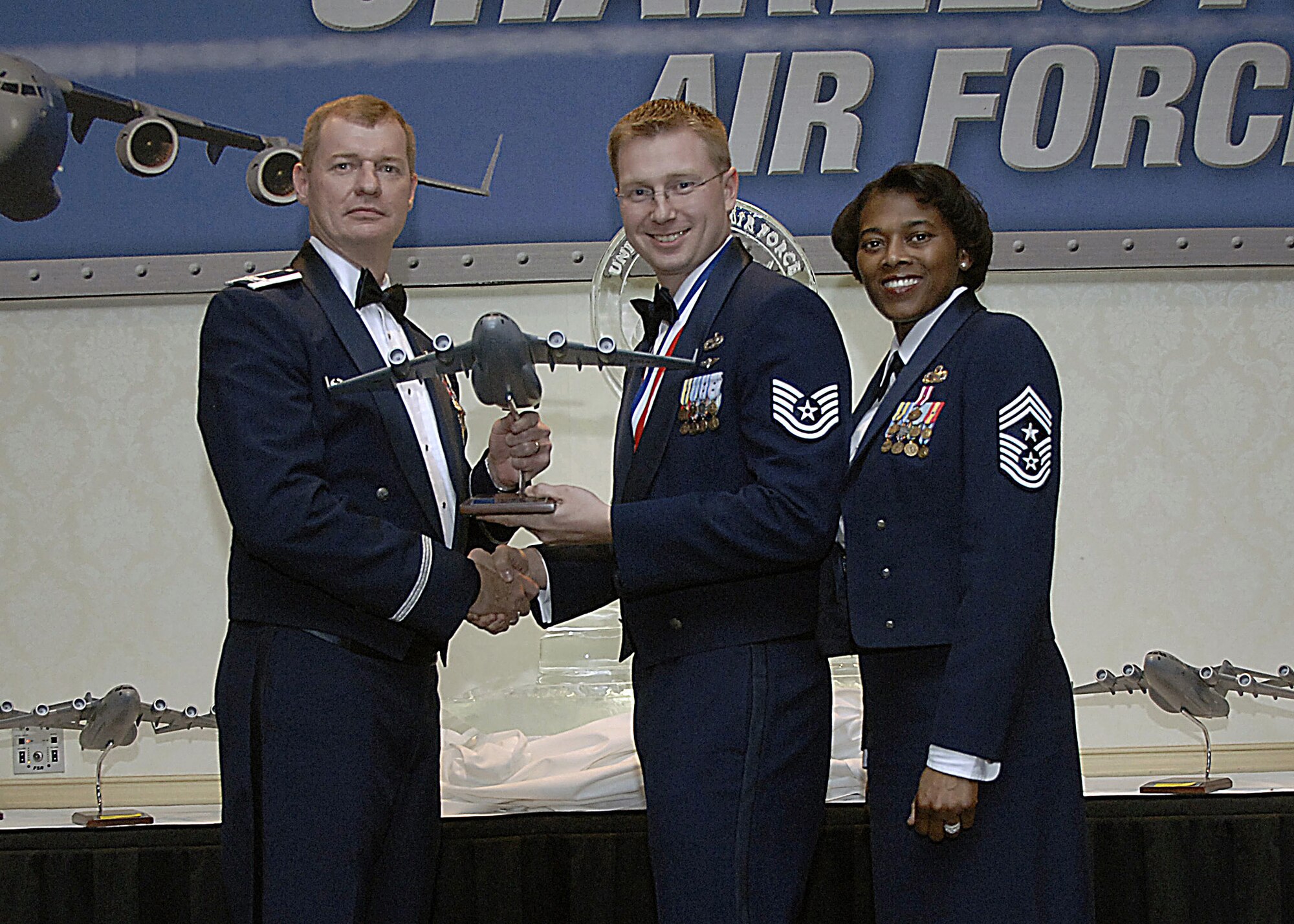 Col. John "Red" Millander, 437th Airlift Wing commander, and Chief Master Sgt. Bernice Belcer, 437th Airlift Wing command chief master sgergeant, present the 437th Airlift Wing NCO of the Year award to Tech. Sgt. Ricky Smith, 437th Aerial Port Squadron, at the 437 AW Annual Awards dinner at the Charleston Club Jan. 24. (U.S. Air Force photo/Airman 1st Class Katie Gieratz)