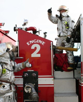 Sra Matthew Hau, left, and Staff Sgt Scott Lair, 507th Air Refueling Wing, stand ready during a Fire Department crew extraction exercise.  Sergeant Lair is requesting the “ready” signal from the hose crew to charge the line thus allowing rescue crew members to gain entry into the aircraft.