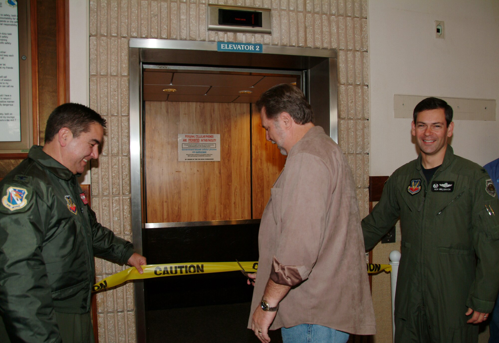 Former 53d Wing building custodian Roger Holley came out of retirement to officially cut the ribbon on the “new and improved” Elevator #2 Jan. 29 at the wing headquarters building.  Mr. Holley is flanked on the left by Col. Mick Guthals, 53d Wing vice commander and Col. Ken Wilsbach, wing commander.  The renovation of the elevator was a work in progress for two years. Mr. Holley took the first ride up with the wing and vice commanders as well as the crew who fixed the elevator.  Air Force photo by Staff Sgt. Samuel King Jr.