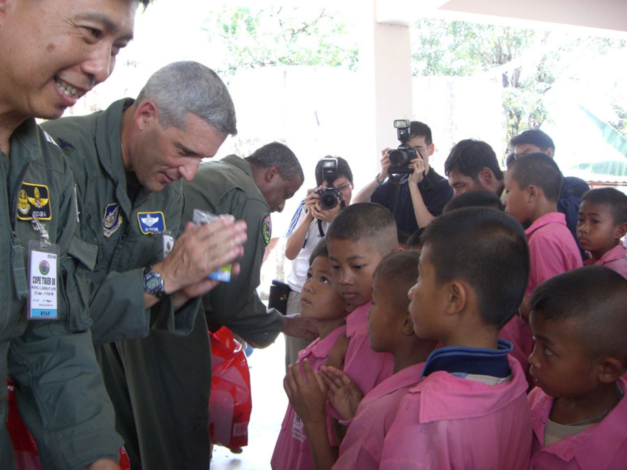KORAT, Thailand -- Col. James Horton (center), 13th Air Expeditionary Wing commander for Exercise Cope Tiger 2008, returns a 'wai' to young Thai students of Ban Don Phawa School in a rural village outside of Korat, Thailand Jan. 30. The colonel, along with Group Captain Suksom Sukasam, Royal Thai Air Force deputy exercise director (left) and Col. Anil Sankar, Republic of Singapore Air Force exercise director, presented equipment donations to the school as a part of a humanitarian mission. (U.S. Air Force photo by Capt. Renee Lee)