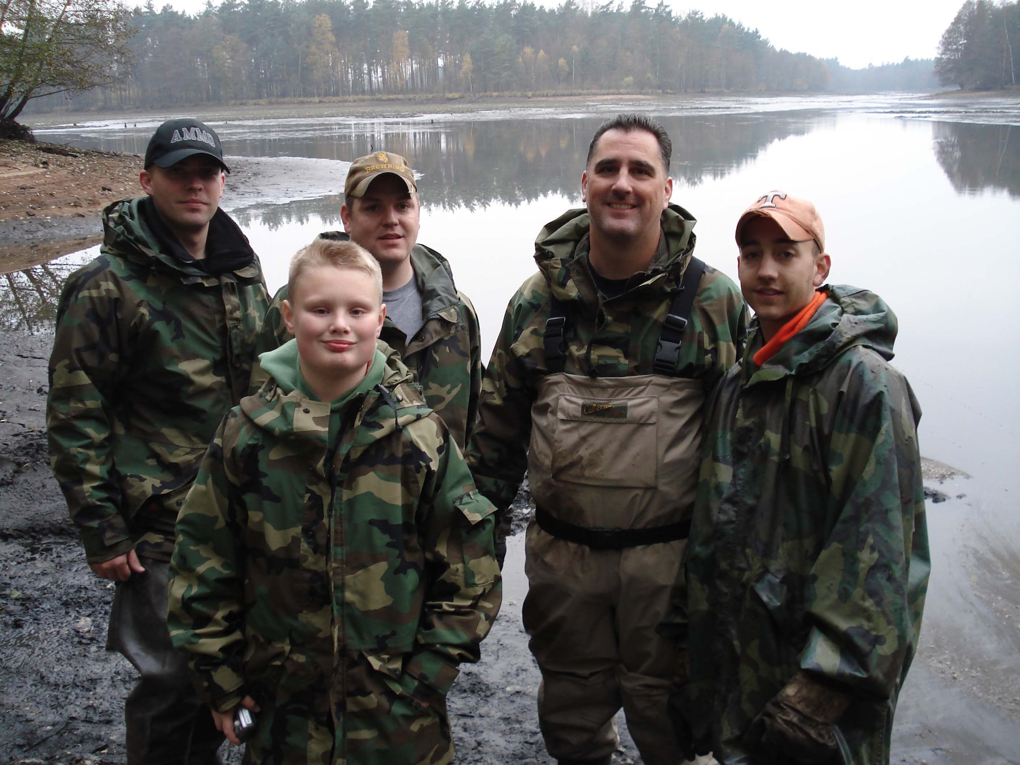 Staff Sgt. David Kieper, Zachary Windorf, Airman 1st Class Jeremy Burney, Master Sgt. Scott Windorf, and Airman 1st Class Jonathan Farmer stand in front of the lake that was drained to evict its large wells catfish. (Courtesy photo)

