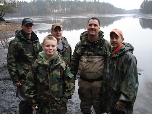 Staff Sgt. David Kieper, Zachary Windorf, Airman 1st Class Jeremy Burney, Master Sgt. Scott Windorf, and Airman 1st Class Jonathan Farmer stand in front of the lake that was drained to evict its large wells catfish. (Courtesy photo)

