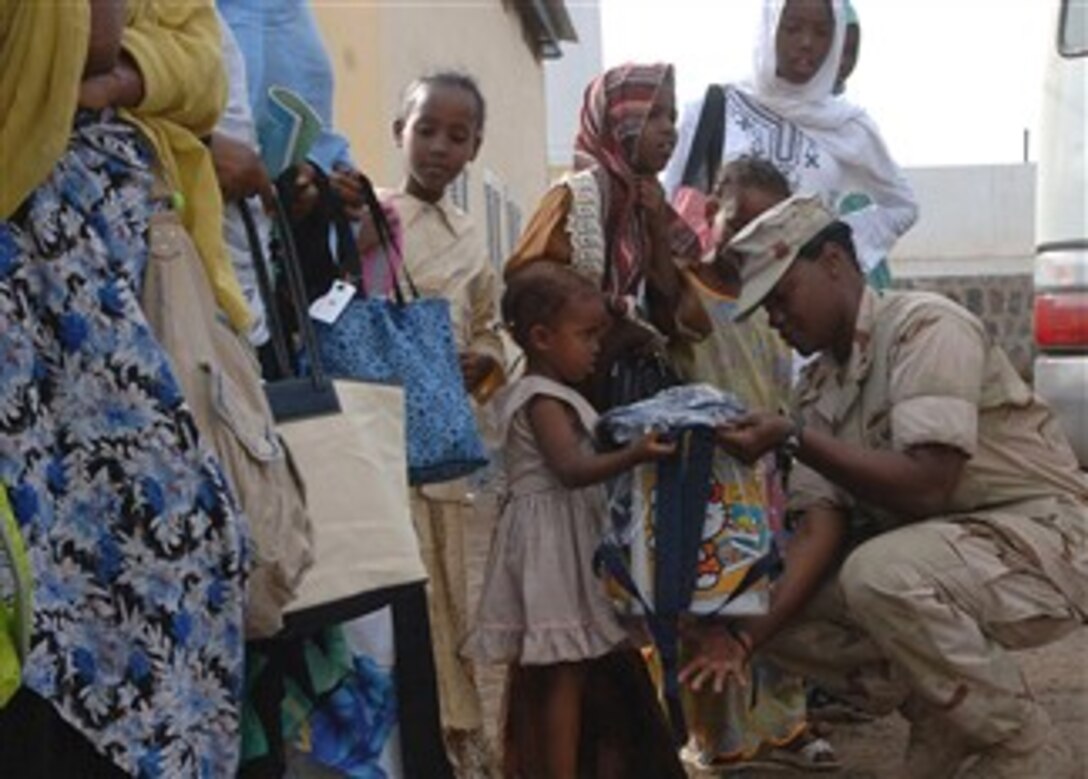 U.S. Navy Senior Chief Legalman Alicia Barnes hands a book bag containing school supplies, flip flops, soap, shampoo and treats to a young girl Jan. 27, 2008, at the Center for the Protection of Women and Children in Djibouti, the country's largest orphanage.