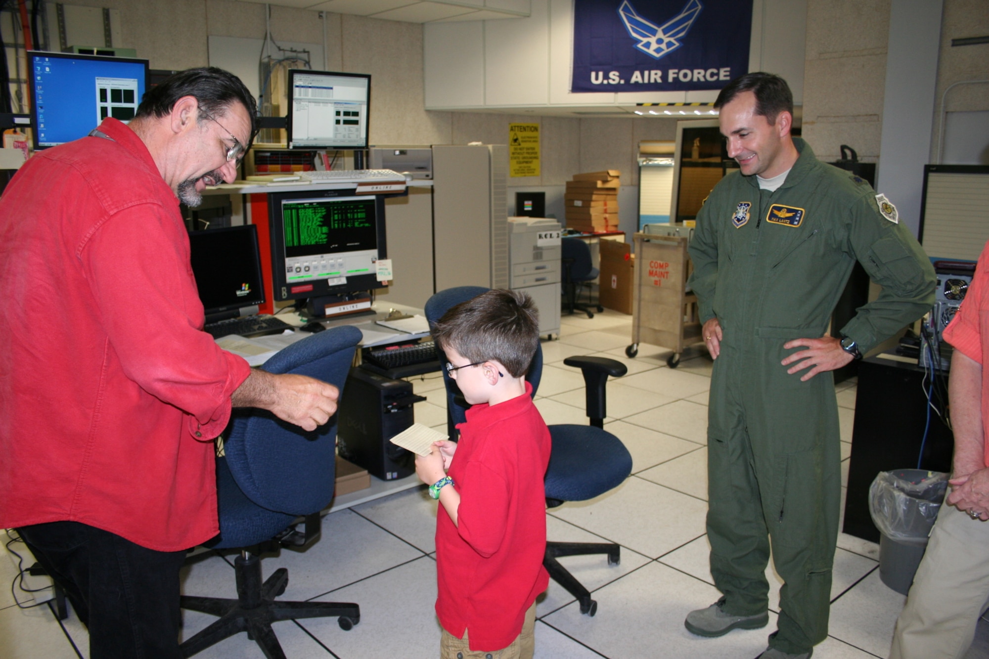 Lt. Col. Max Lantz, new 6th Space Warning Squadron commander, smiles as his son, Max E. Lantz III, accepts a punchcard from Dave “CyberDave” Zysek, Computer Lead with BAE Systems for the Pave PAWS radar at Cape Cod AFS.  The punchcard is a relic from this radar’s early days in the 1980s, and an appropriate gift to mark the Cyber Legacy Emulator Upgrade BAE Systems helped the Air Force complete last year.  Although the original Cyber system worked flawlessly, the upgrade allows for sustainability with off-the-shelf parts.  Colonel Lantz took command of the 6th SWS June 25.