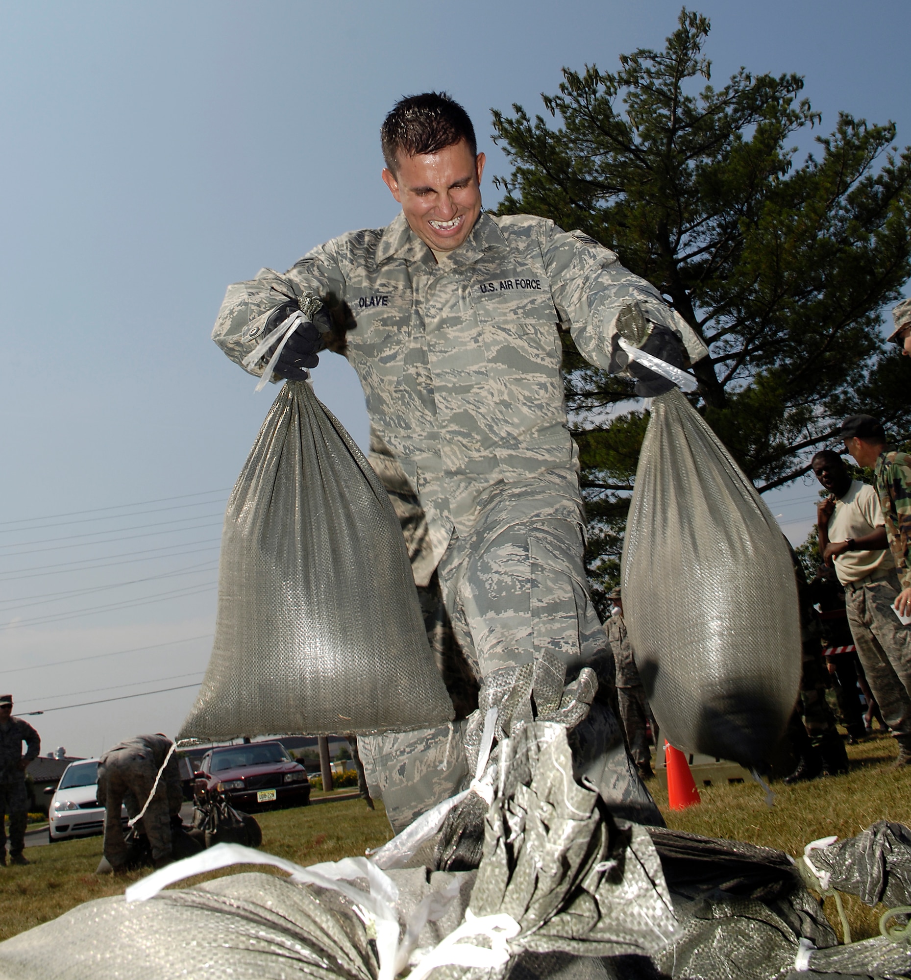 Senior Airman Oscar Olave, 817th Global Mobility Squadron, carries two 50-pound bags of sand to a circle before continuing on the obstacle course during the 621st Contingency Response Wing Combat Field Day June 27 here. The field day consisted of numerous events, including the ruck-sack relay, tent building and an obstacle course. (U.S. Air Force photo/Kenn Mann)