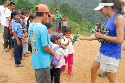 SOTO CANO AIR BASE, Honduras?Air Force Capt. Kenya Colon hands a child a stuffed animal during the June Chapel Hike to the tiny village of Picacho, Honduras. (U.S. Air Force photo by Tech. Sgt. William Farrow)